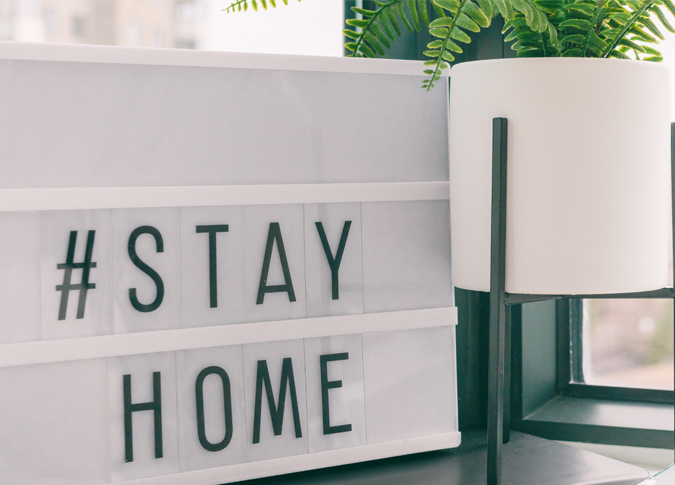 small sign on a desk that reads #stay home