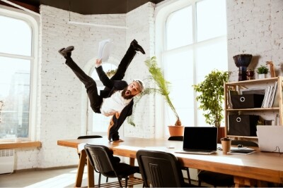 a businessman in an office jumps high in the air to celebrate